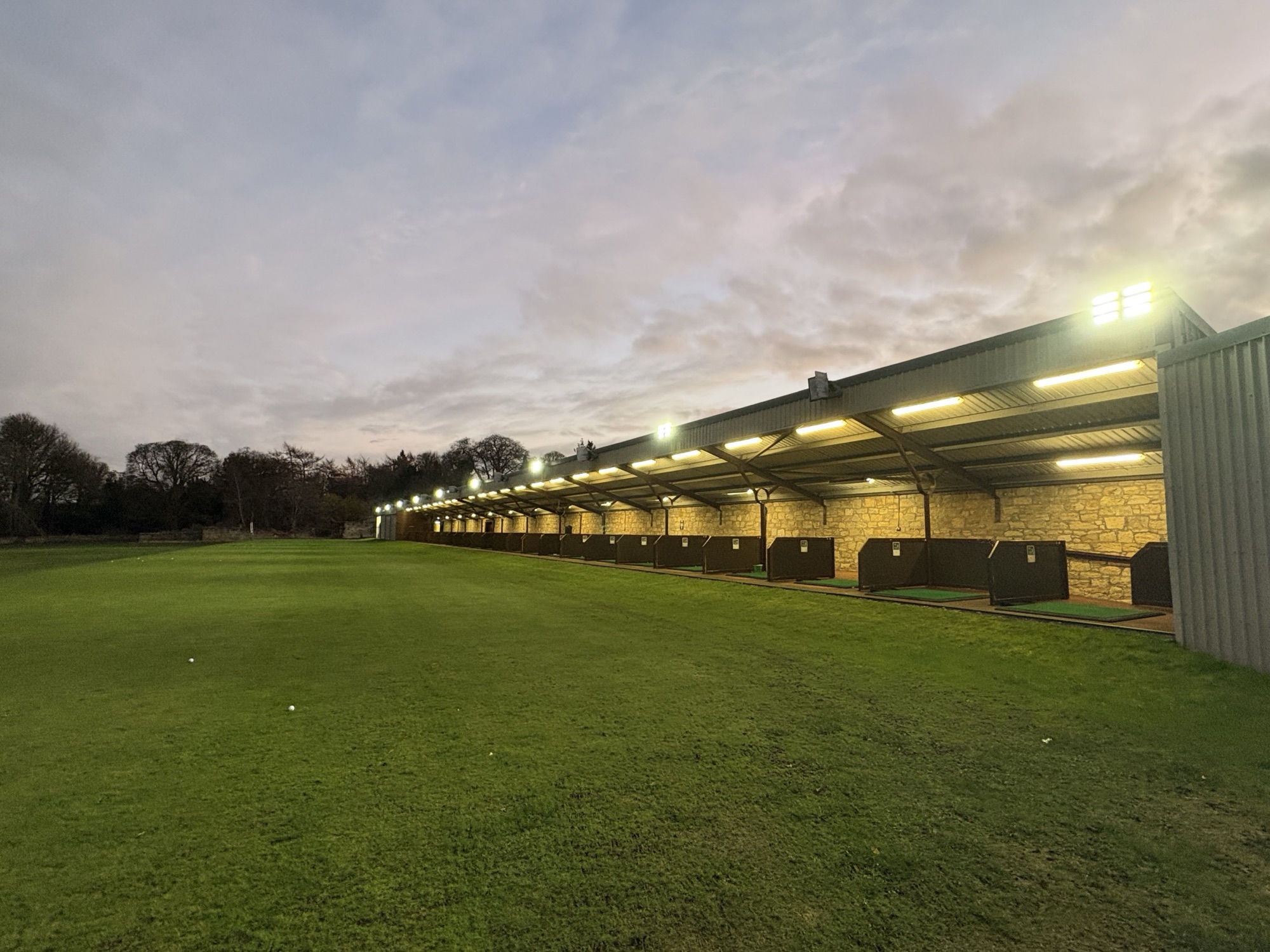 The Kings Acre driving range bays under an evening sky